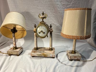 trois lampes et une horloge posées sur une table