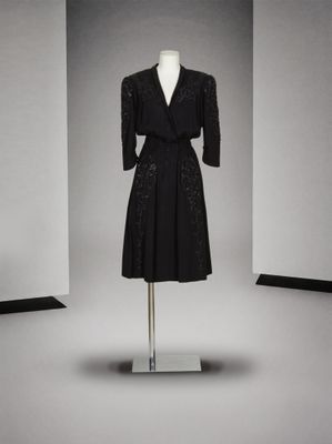 une robe noire posée sur un mannequin devant un mur blanc