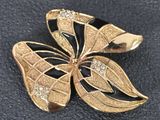 broche papillon noire et dorée, ornée de cristaux transparents sur un fond noir