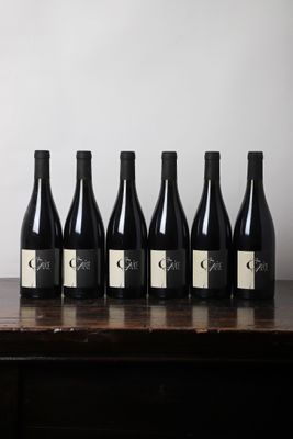 six bouteilles de vin sont posées sur une table devant un mur blanc