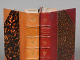 three books are stacked on top of each other on a gray surface