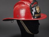 a red fireman ' s hat with a badge on it
