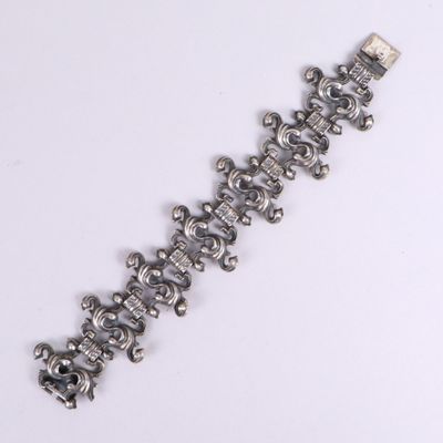 une image représentant un bracelet en argent orné de têtes de mort, posé sur un fond blanc