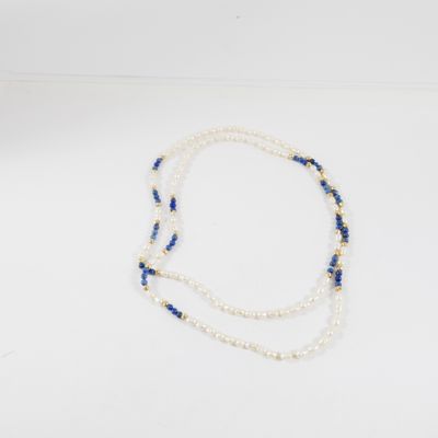 un collier de perles blanches et bleues posé sur une surface blanche