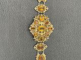 a close up of a gold and orange bracelet on a gray surface