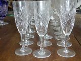 six verres à vin posés sur une table, avec un vase bleu en arrière-plan