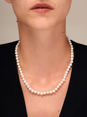 une femme portant un collier de perles et une robe noire