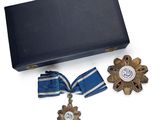 une boîte contenant une médaille, un ruban et une croix