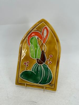 une photo d'une broche jaune et verte sur laquelle figure un oiseau