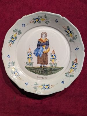 une assiette sur laquelle est représentée une femme assise sur une souche d'arbre