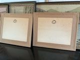 two picture frames sitting on a table next to each other