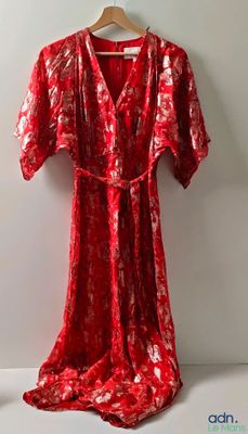 une robe rouge suspendue à un cintre près d'un mur blanc