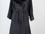 un manteau noir à col de fourrure sur un mannequin