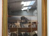 a gold framed mirror hanging on a wall in a store