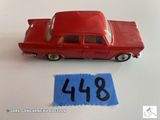 une petite voiture rouge posée à côté d'une feuille de papier bleue