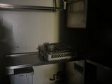 une petite cuisine équipée d'une cuisinière, d'un évier et d'une poubelle