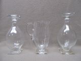 trois vases en verre posés l'un à côté de l'autre sur une table