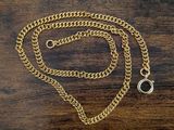 a close up of a gold chain with a ring on a wooden table