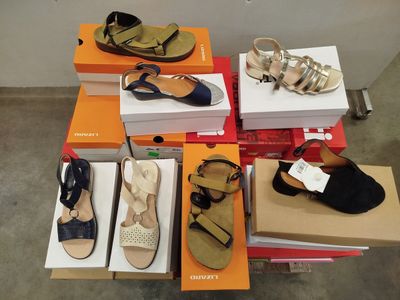 Plusieurs paires de chaussures sont empilées sur des cartons dans une pièce
