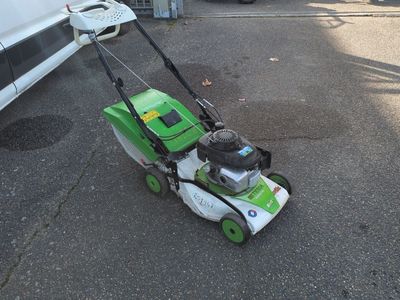 a green and white lawn mower sitting on the street