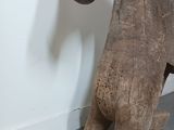 someone is holding a wooden horse statue in front of a white wall