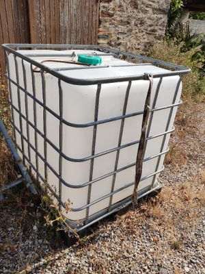 a large container sitting on the ground next to a wooden fence