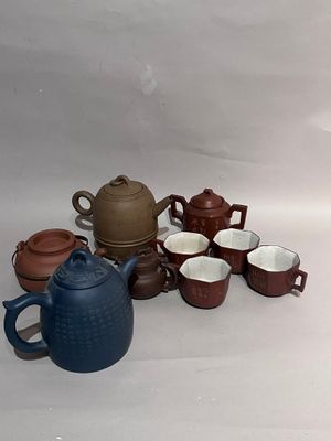 de nombreuses tasses et théières posées sur une table
