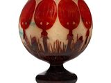 a red and white vase sitting on top of a black stand