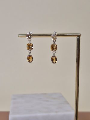une paire de boucles d'oreilles posée sur un présentoir, avec un bloc de marbre en arrière-plan