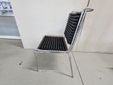 a metal chair with a black seat and a white wall