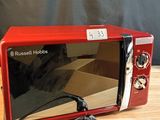 a red microwave oven sitting on a wooden table