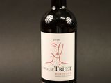 the bottle of red wine is sitting on a black surface