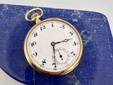 une montre de poche en or posée sur une dalle de marbre bleu