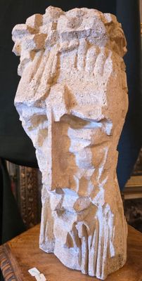 une sculpture représentant une tête d'homme posée sur une table en bois