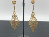 une paire de boucles d'oreilles en or posée sur un support noir