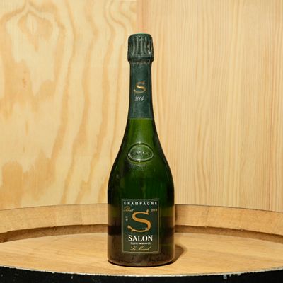 a bottle of wine sitting on top of a wooden barrel