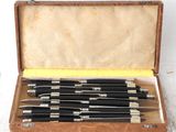 six knives in a wooden case on a white surface