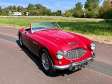 une voiture rouge qui roule sur une route de campagne