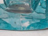 a blue glass candle holder on a white table