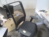 une chaise de bureau noire sur laquelle est posé un écran d'ordinateur