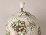 a white vase with a bunch of green and red berries on it