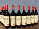 six bottles of red wine lined up in a row on a wooden table