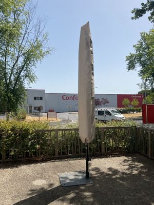 un parapluie blanc posé sur un support devant une clôture