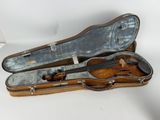 a violin in a case sitting on a white surface