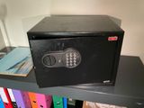 a safe box sitting on top of a book shelf