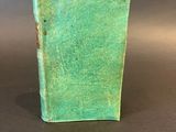 an old green book sitting on top of a black table