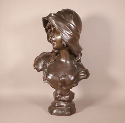bronze bust of a woman with a hat on her head