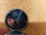 a hand that is holding a silver clock on a table