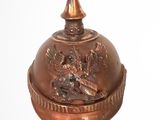 a small copper bell with a bird on it