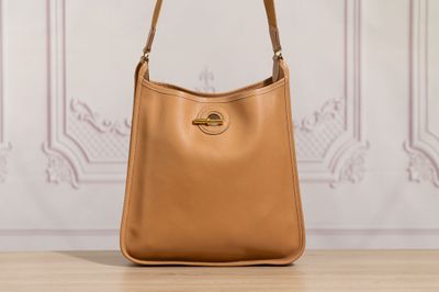 a tan leather handbag sitting on top of a wooden table